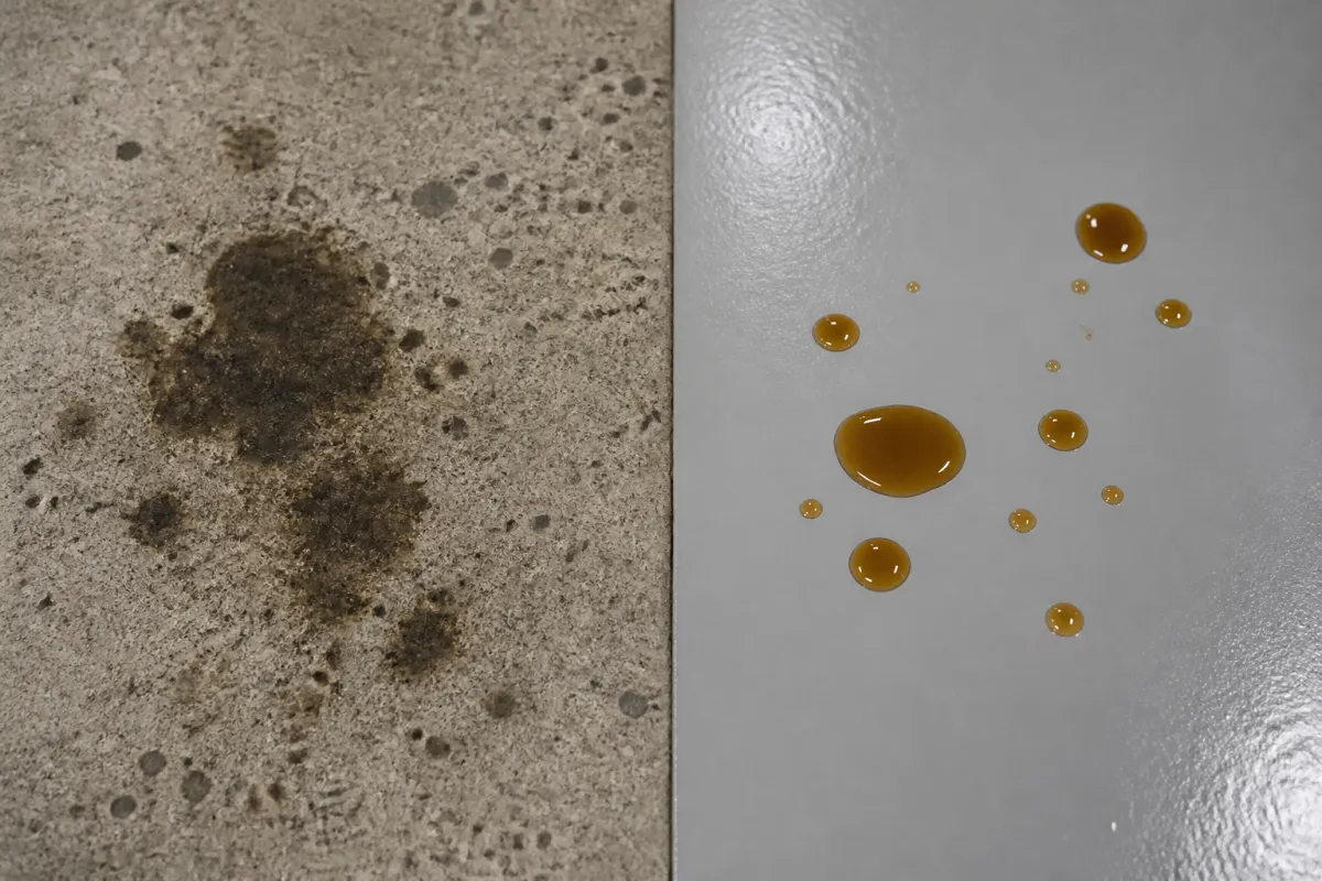 Side-by-side close-up: bare grey concrete with dark oil stains soaked in on the left, and a smooth glossy grey coated floor with oil drops sitting on the surface on the right